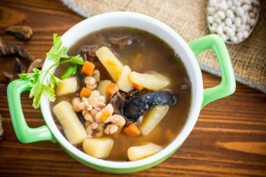 mushroom hot soup with beans in a bowl, on a rustic burlap tablecloth.