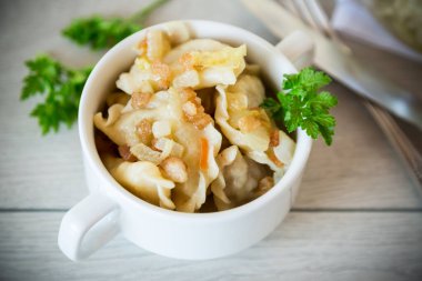 Tahta bir masada patates ve kızarmış soğanla pişirilmiş hamur köftesi..