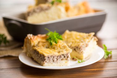 Pişmiş et turtası, ahşap bir masada tabakta parçalar..