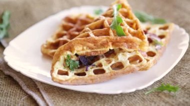 Soğan ve otla doldurulmuş yumurta omleti, waffle şeklinde kızartılmış, ahşap bir masada.