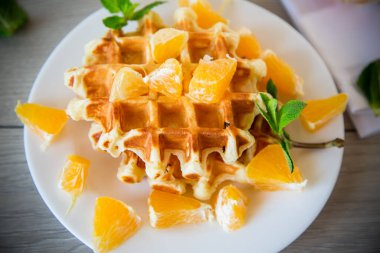 Tahta bir masada portakallı Belçika waffle 'ı pişirdim..