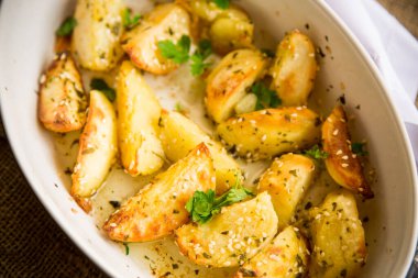 Patatesler susam tohumları, otlar ve baharatlarla fırında seramik bir şekilde pişirildi..