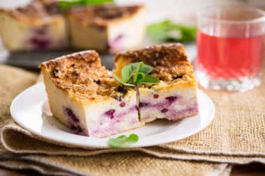 Pişmiş süzme peynir güveci ve masada böğürtlen dolu bir tabak.