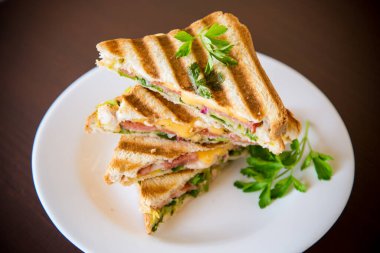 İçinde sosis, peynir ve sebzeyle doldurulmuş kızarmış ekmek, masada bir kasede...