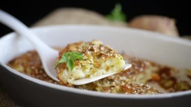 potato casserole with cabbage and spices in a ceramic form on a wooden table.