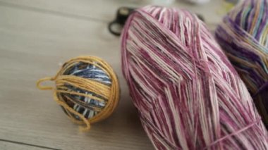 Colored threads, knitting needles and other items for hand knitting, on a light wooden table .