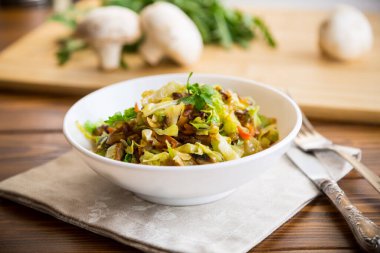 Tahta bir masada mantar, havuç ve sebzelerle kızartılmış lahana.