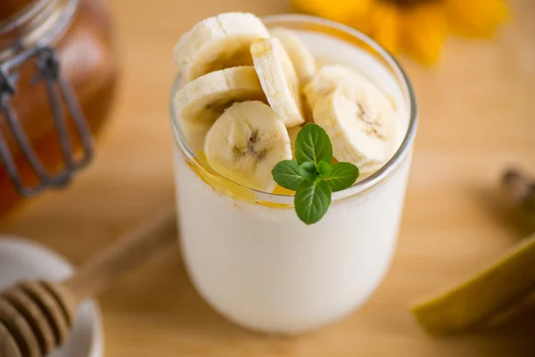甜的自制酸奶 配香蕉和蜂蜜在杯子里 图库图片