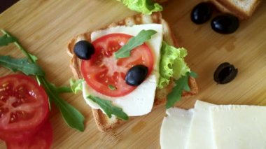 Kızarmış ekmek, mozarella, marul ve domatesli ahşap bir masada.