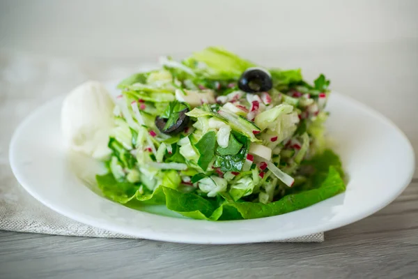 キャベツやキュウリや大根などの野菜が入った新鮮な夏のサラダを木のテーブルの上の皿に盛ります — ストック写真