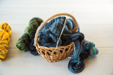 Renkli iplikler, örgü iğneleri ve el örgüsü için diğer malzemeler, koyu ahşap bir masa üzerinde. .