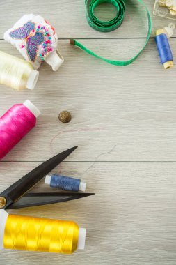 Ahşap bir arka planda dikiş giysileri için bir takım alet ve iplikler..