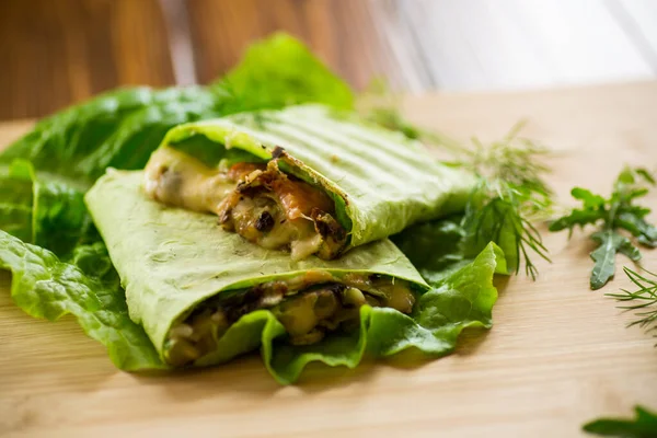 キノコと野菜が入ったグリーンホットベジタリアンピタパン木のテーブルの上にレタスの葉 — ストック写真
