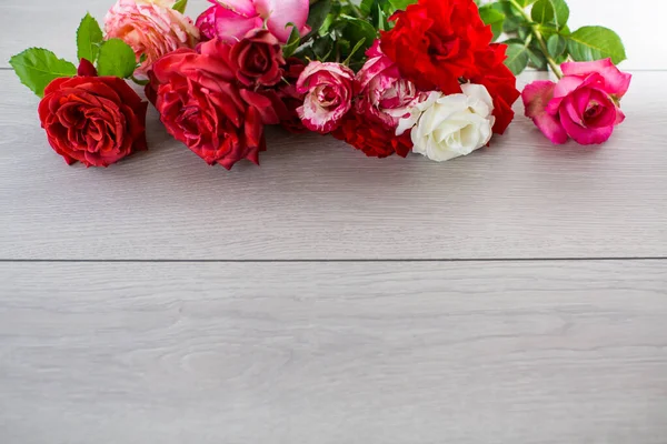浅色木制桌子上的粉红色 红色和其他玫瑰的花朵背景 — 图库照片