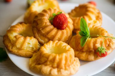 Tahta bir masada taze çilek ve nane şekerli kaymaklı kek pişirdim..