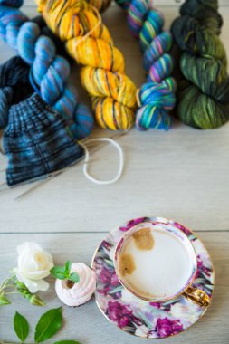 Colored threads, knitting needles and other items for hand knitting, on a light wooden table .