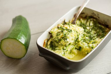 Fırındaki omlette pişmiş yeşil kabak, ahşap bir masada seramik formda..