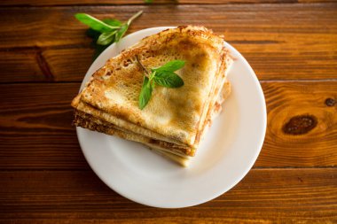 Koyu ahşap bir masada, tabakta bir sürü ince krep..