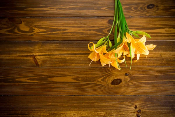 暗い木製のテーブルの上に美しい黄色のユリの花束 — ストック写真