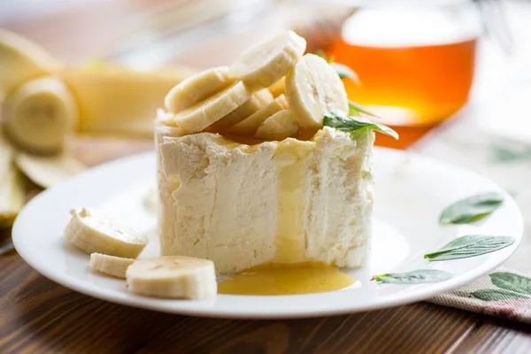 自制牛奶凝乳配以香蕉片和蜂蜜 薄荷放在盘子里 — 图库照片