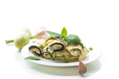 Beyaz arka planda izole edilmiş bir tabakta içi peynirle doldurulmuş kabaklı börekler.