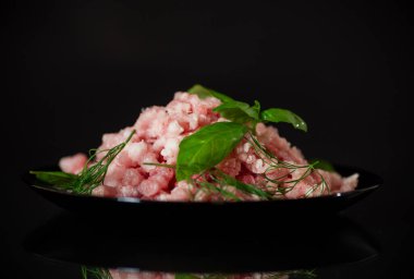 Bir tabakta doğranmış taze domuz eti, siyah arka planda izole edilmiş..