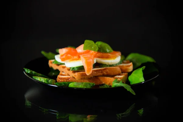 用少许咸红鱼 煮熟的鸡蛋和香草做三明治 用黑色底色隔开 — 图库照片