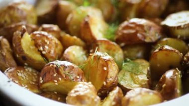 Patatesler susam tohumları, otlar ve baharatlarla fırında seramik bir şekilde pişirildi..