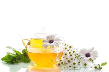 Papatya çiçeği çayı, cam bardak ve çaydanlıkta, beyaz arka planda izole edilmiş..