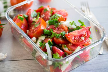 Baharatlı atıştırmalık domatesler, sarımsak, otlar, baharatlar ve soğanlar ahşap bir masada cam kasede..