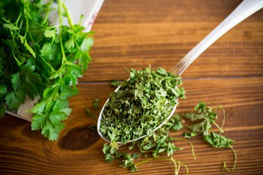 Tahta bir masada, taze otların yanında kurutulmuş maydanoz..