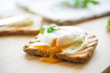 Ahşap bir masada, saçılmış yumurta ve haşlanmış tost ekmeği. Hızlı kahvaltı..