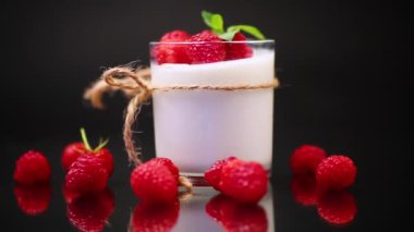 Siyah arka planda izole edilmiş, olgun kırmızı ahududulu ev yapımı yoğurt.