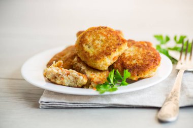 Hafif ahşap bir masada, otlarla dolu bir tabakta kızartılmış balık pirzolası..