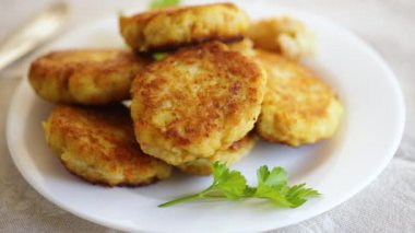 Hafif ahşap bir masada, otlarla dolu bir tabakta kızartılmış balık pirzolası..