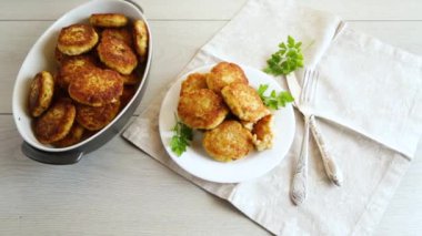 Hafif ahşap bir masada, otlarla dolu bir tabakta kızartılmış balık pirzolası..