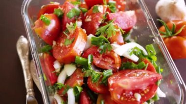 Baharatlı atıştırmalık domatesler, sarımsak, otlar, baharatlar ve soğanlar ahşap bir masada cam kasede..