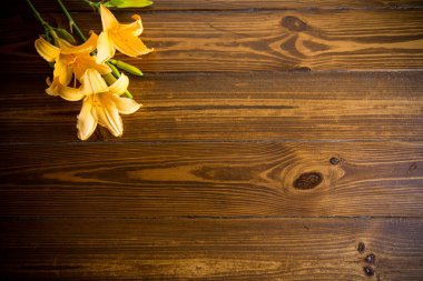 Koyu ahşap bir masada güzel sarı zambaklar.