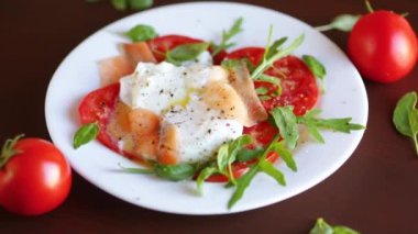 Pişmiş haşlanmış yumurta, sebzeli, hafif tuzlu somon ve ahşap bir masada baharatlı domates..