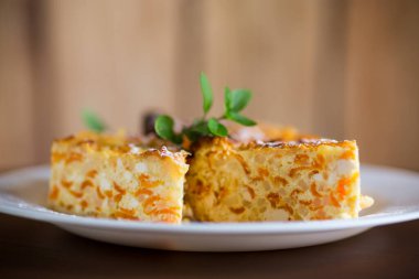 Ahşap bir masada içinde balkabağı parçaları olan süzme peynir güveci..