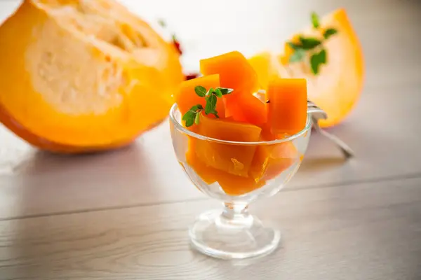 Prepared sweet pumpkin marmalade in a glass bowl on a wooden table. Autumn recipes.
