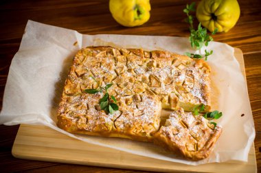 İçinde baldıran ve ahşap bir tahtanın üzerinde pudra şekerle kaplanmış kaymaklı irin turtası..