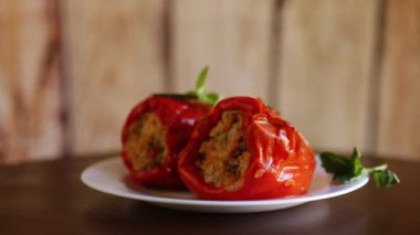 Doldurulmuş biberler içinde ahşap bir masada, bir tabakta.