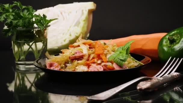 用蔬菜和腊肠烹调的炸卷心菜 放在一个用黑色底盘隔开的盘子里 — 图库视频影像