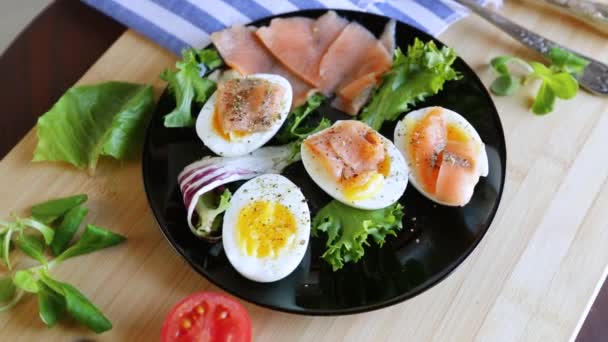 木のテーブルの皿に塩漬けの赤魚 ハーブ 調味料が付いている卵 — ストック動画