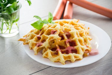 Kızarmış patates waffle 'ı, içinde sosis olan ahşap bir masada, tabakta..