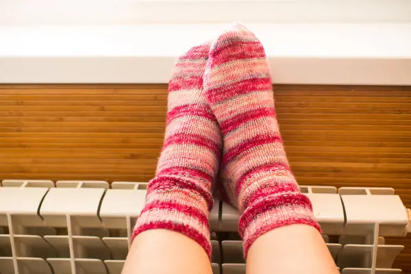 Feet in warm winter socks warm up on the radiator on cold winter days.