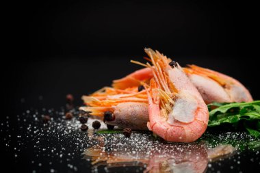 Siyah zemin üzerinde baharatlı haşlanmış karides.