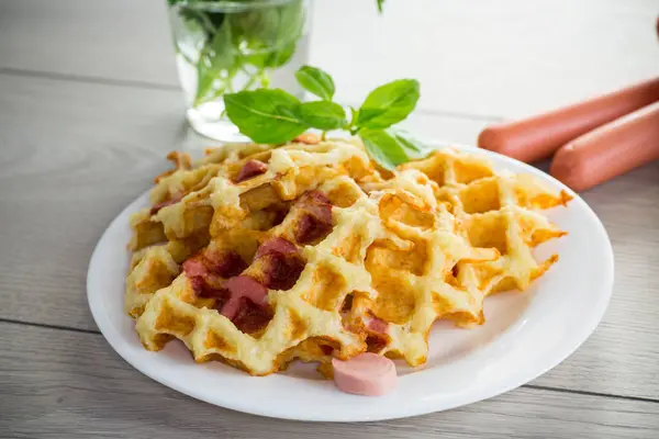 Kızarmış patates waffle 'ı, içinde sosis olan ahşap bir masada, tabakta..