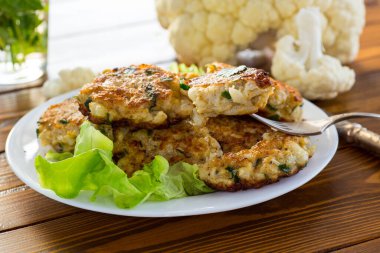 Pişmiş vejetaryen kızarmış karnabahar pirzolası, ahşap bir masada bir tabakta..